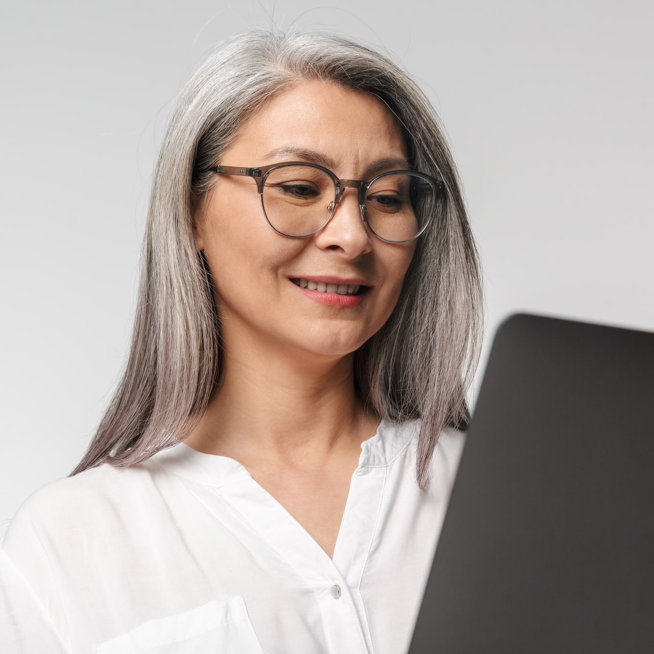 DigiOX – Eine Frau mit Brille lächelt, während sie auf ihren Laptop schaut, glücklich über ihre gelungene Digitalisierung.